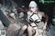 A woman in a black lingerie sitting on a pile of skulls.
