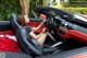 A woman sitting in the driver's seat of a red sports car.