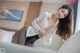 A woman in a white shirt and black stockings posing on a bed.