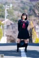 A woman in a school uniform is walking down the street.