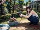 A woman kneeling down with a hose in her hand.