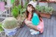 A young woman sitting on a wooden deck next to a cactus.