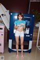 A woman standing in front of a vending machine holding a surfboard.