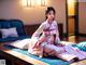 A woman in a pink kimono sitting on a bed.