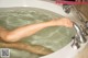 A woman's feet in a bathtub with water coming out of it.